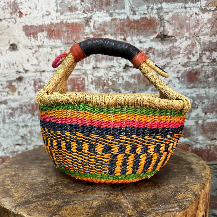 Colorful woven basket with a patterned handle on a wooden surface with a rustic background