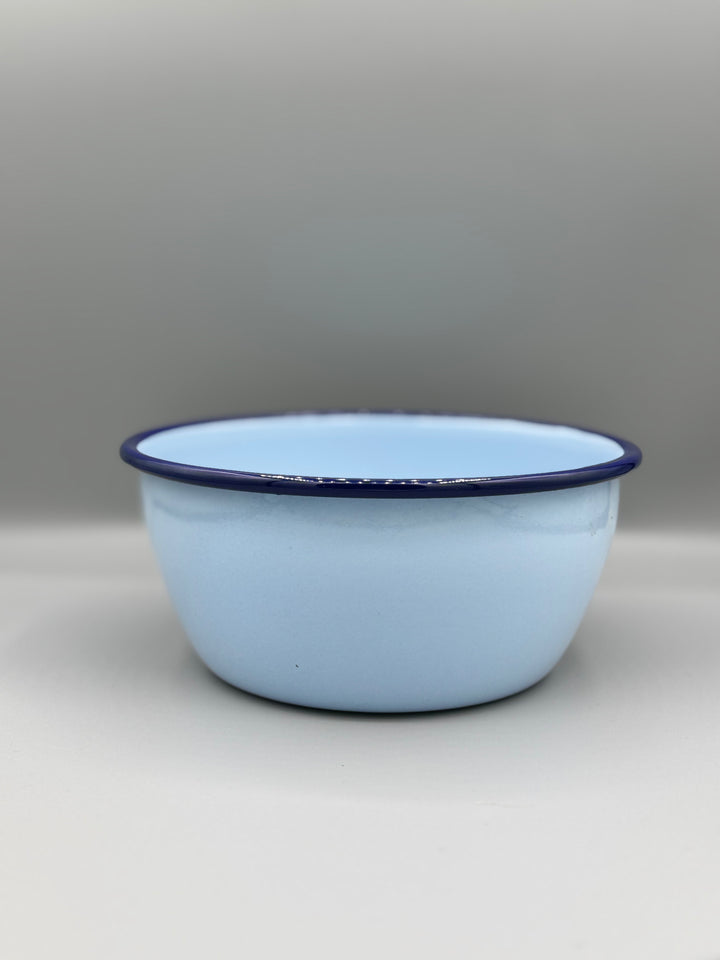 Light blue enamel bowl with a dark blue rim on a light gray background