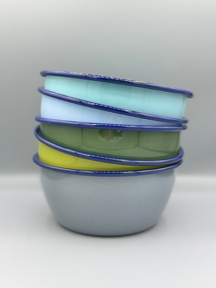 Stack of colorful enamel bowls with blue rims on a white background