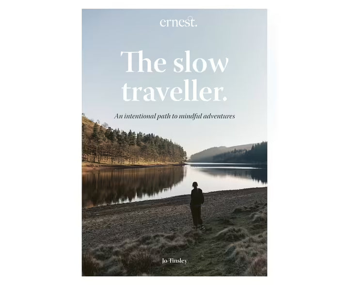 Book cover of 'The slow traveller' by Jo Tinsley with a person standing by a lake.