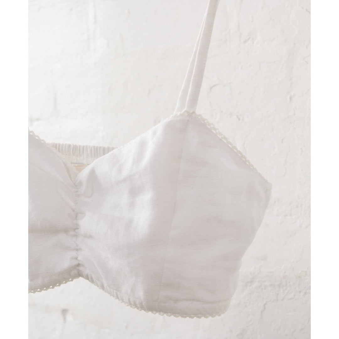 White Bralette in Linen-Jade and May-Bralette- Everyday Essentials- Close up of bralette shown hanging against a white wall