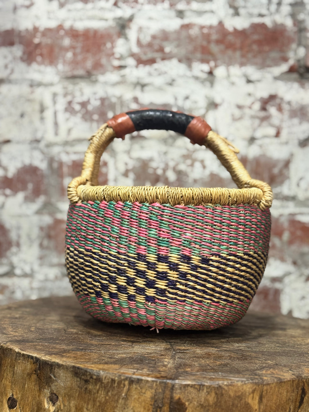 Woven basket with a checkered pattern on a wooden surface with a brick wall background