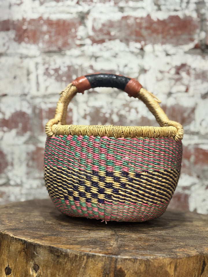 Woven basket with a checkered pattern on a wooden surface with a brick wall background