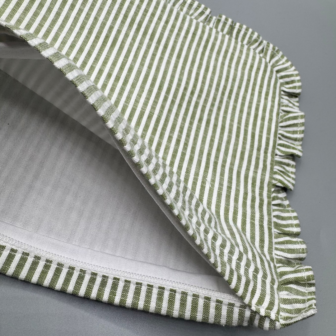 Green and white striped fabric with ruffled edge on a gray background