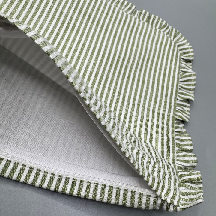 Green and white striped fabric with ruffled edge on a gray background