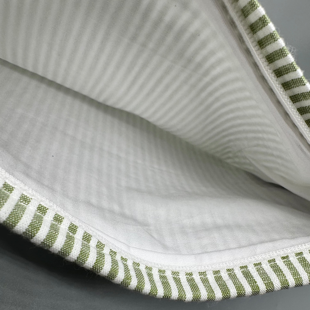 Close-up of a fabric with green and white striped trim on a gray background