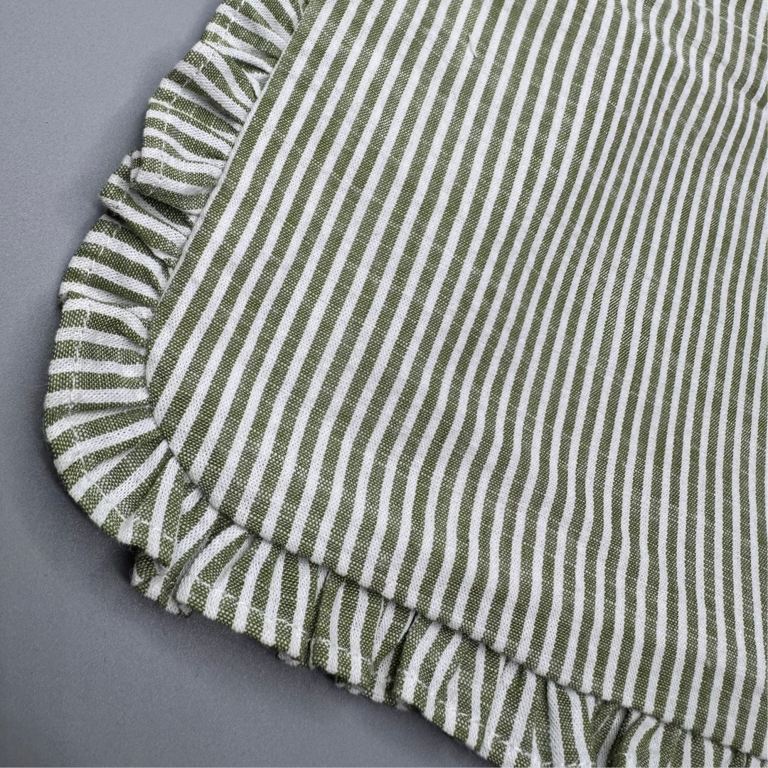 Green and white striped fabric with ruffled edge on a gray background