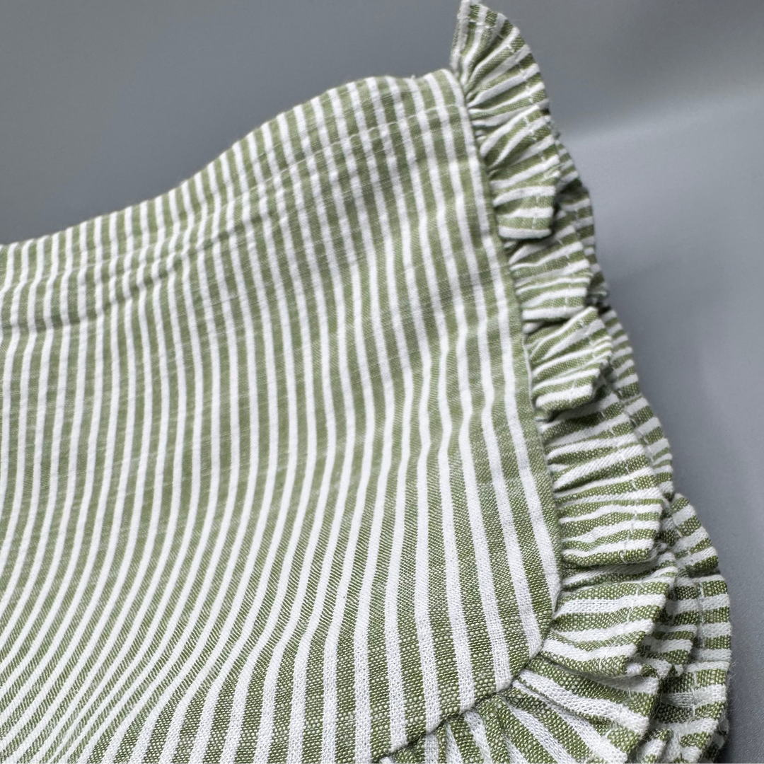 Green and white striped fabric with ruffled edges on a gray background