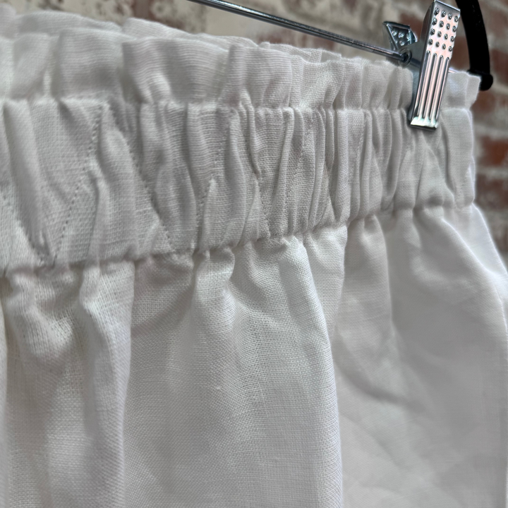 White pants on a hanger against a brick wall background