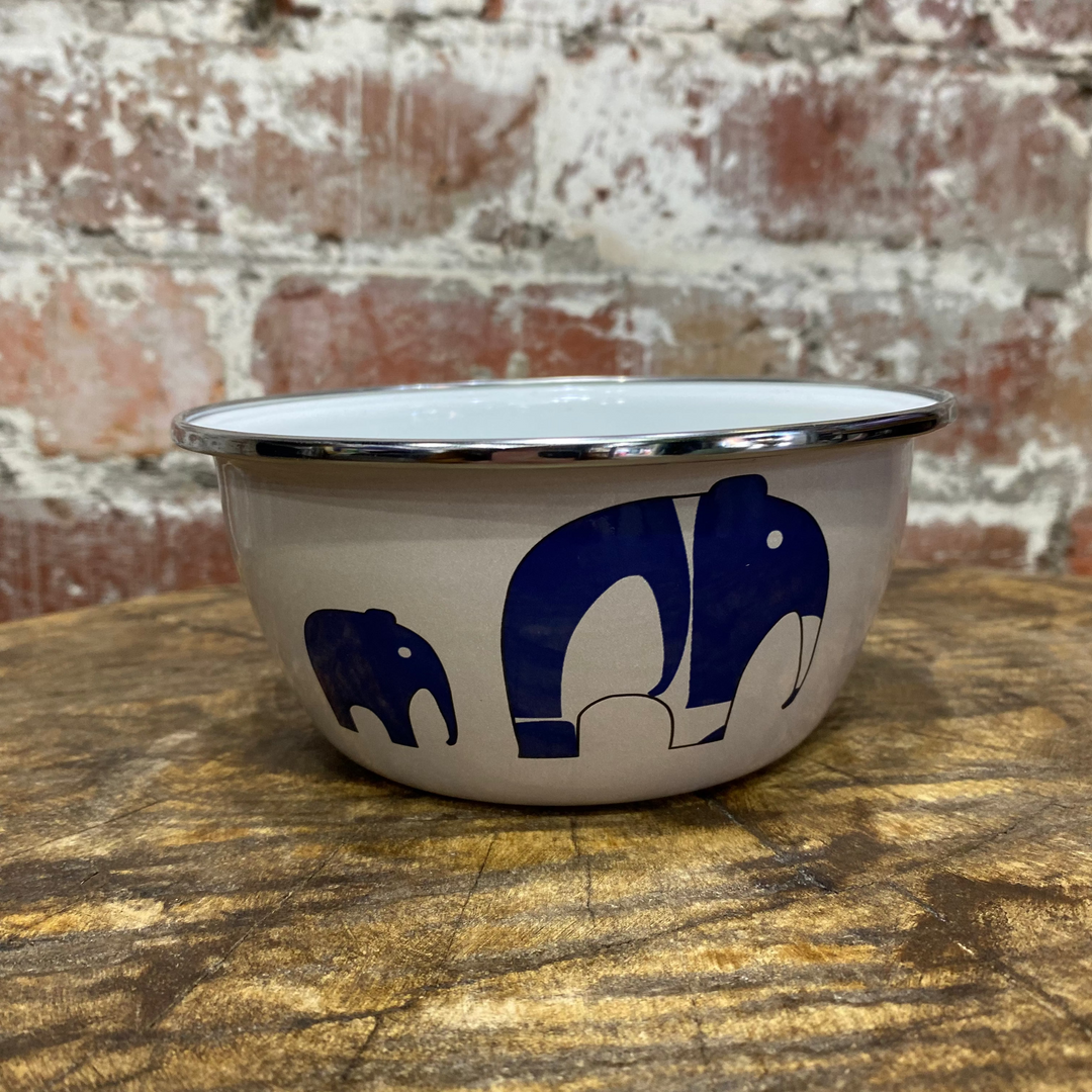 White bowl with blue elephant design on a wooden surface and brick wall background