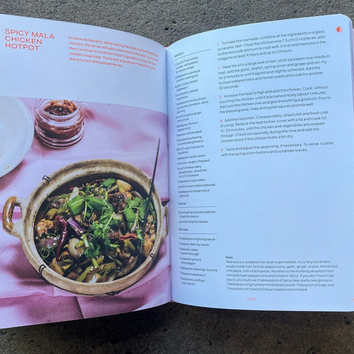 Open cookbook showing a recipe for grilled halloumi chicken with a photo of the dish on a concrete surface.