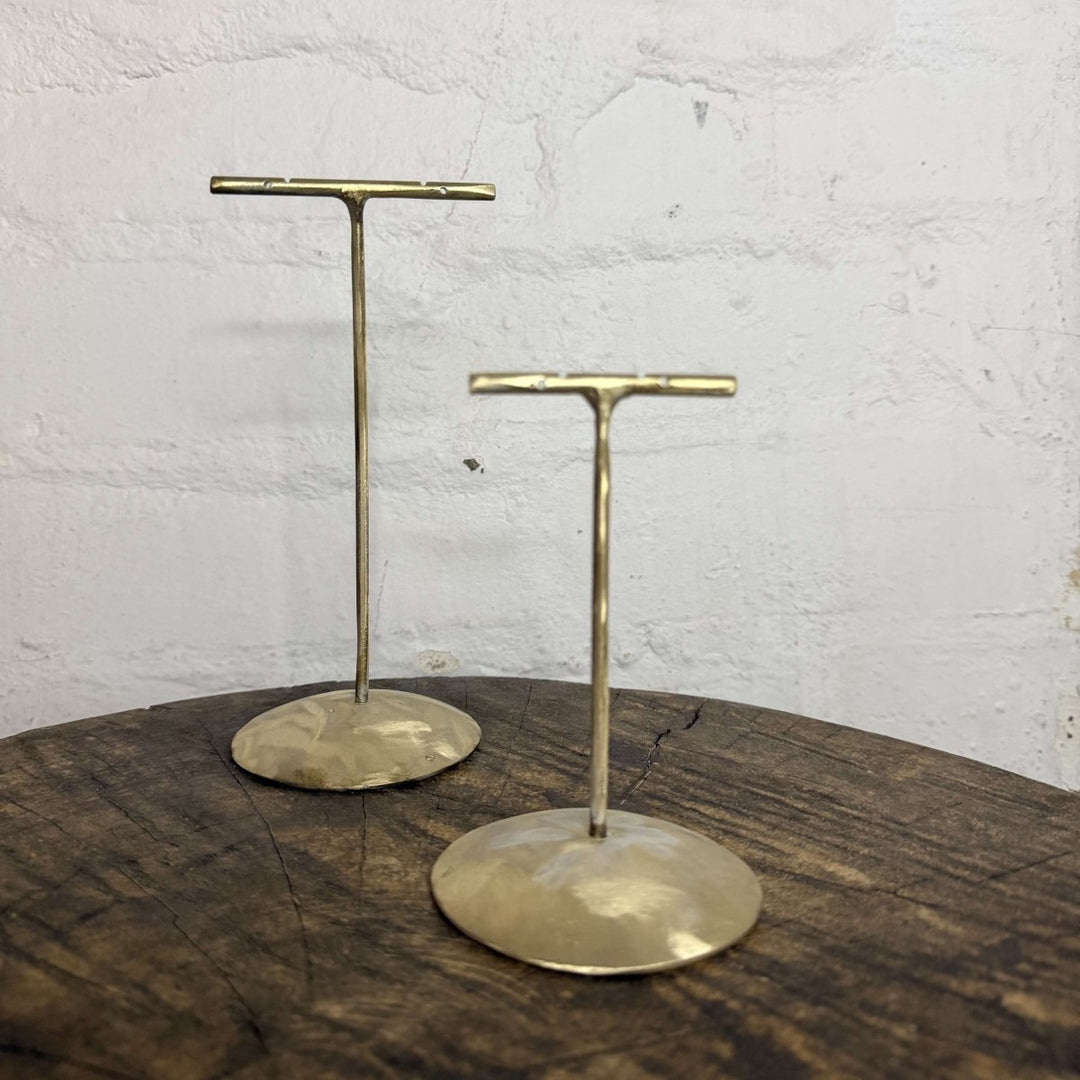 Brass t-stakes with round ends on a wooden surface and white wall background