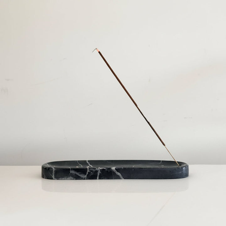 Incense stick in a holder against a plain wall